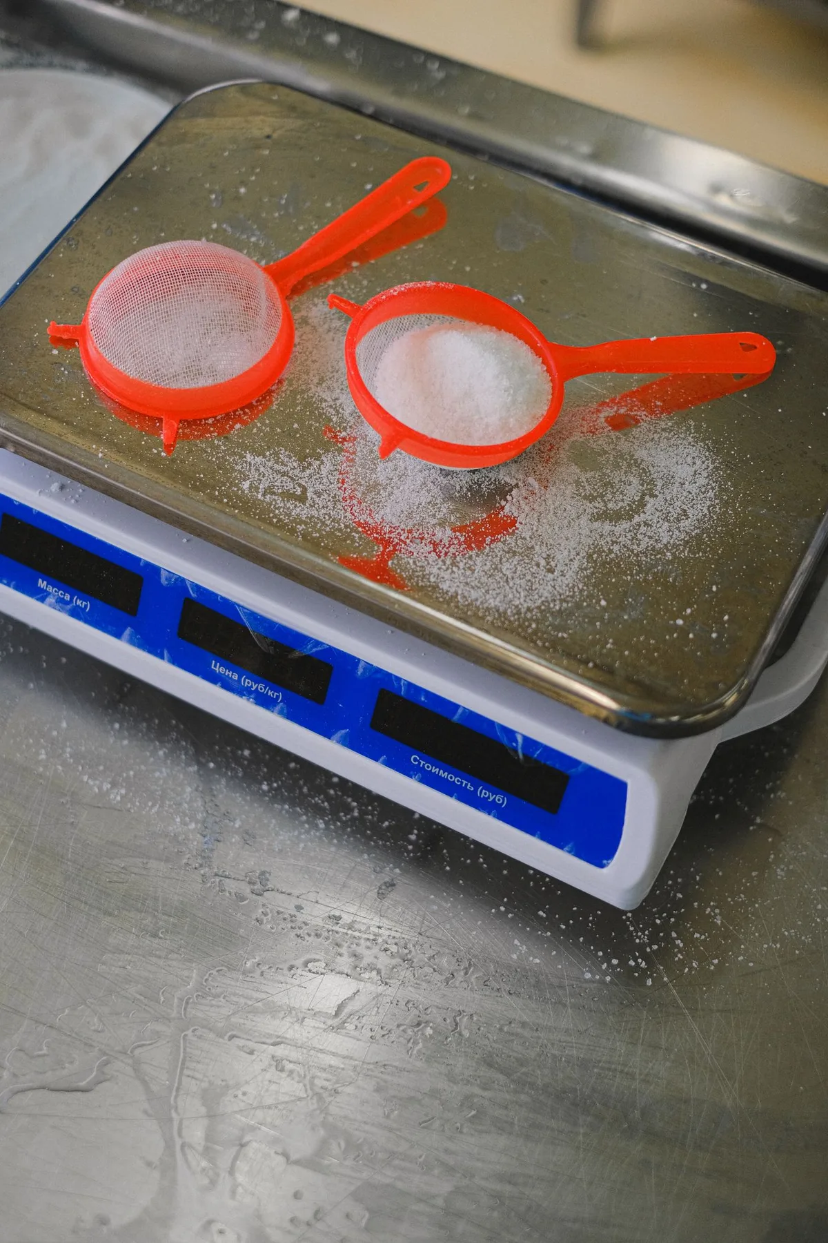 Red sieves holding flour on a digital kitchen scale