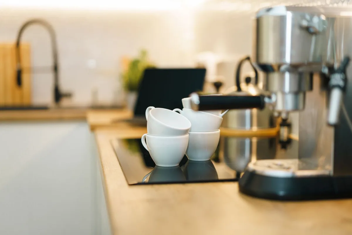 An espresso machine with cups on a kitchen counter