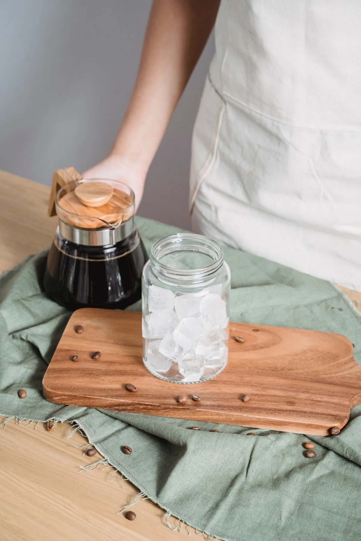 Ice cubes in a glass jar during coffee preparation on a wooden board