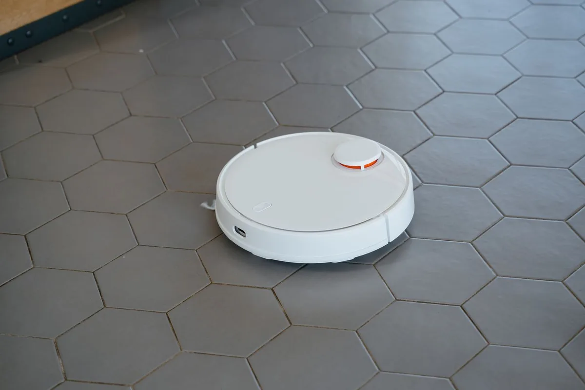 A white robot vacuum on a hexagonal tiled floor
