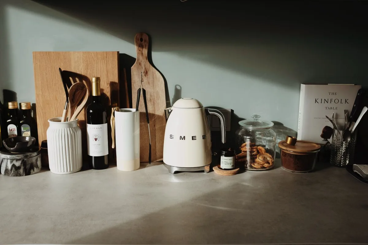 Kitchen counter with a kettle, utensils, cutting boards and stacked bowls