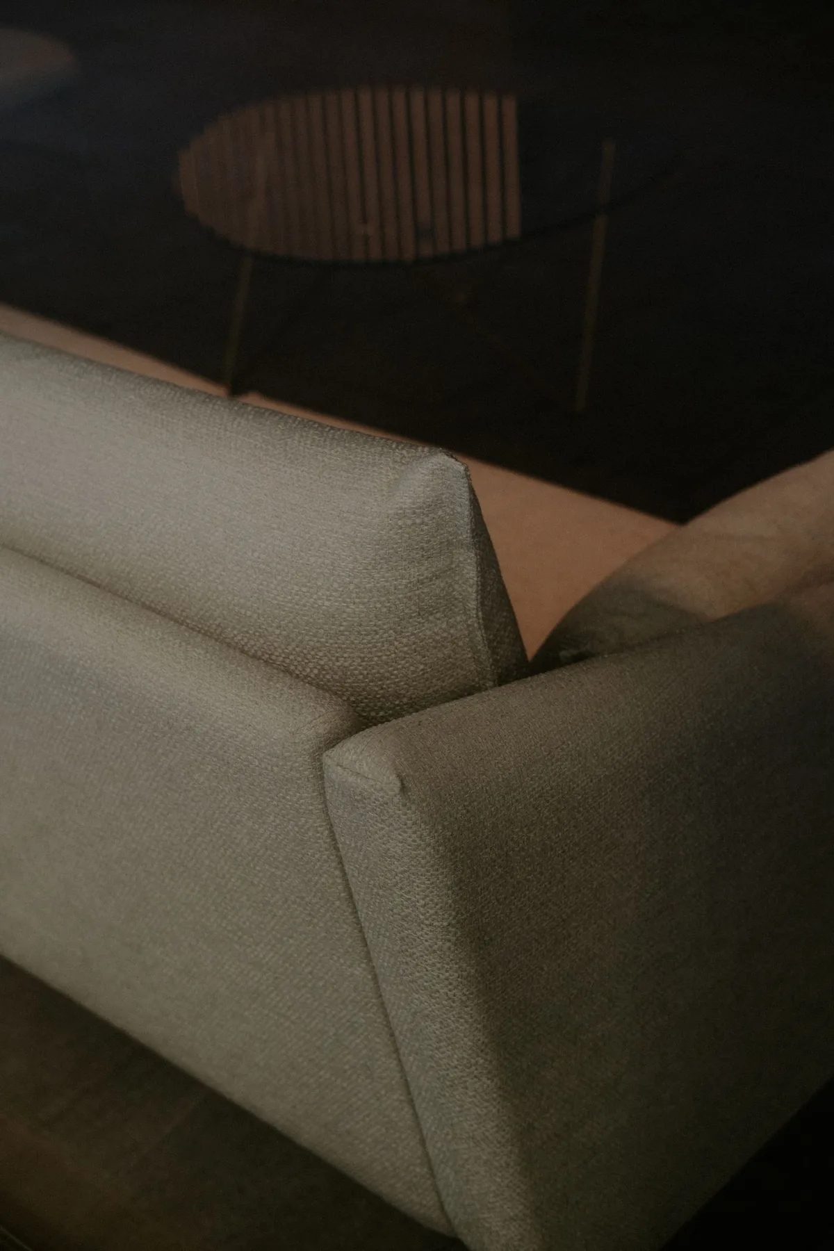 A pale upholstered sofa with a glass coffee table in a minimalist living room